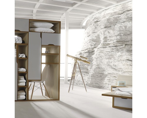 Chambre claire avec armoire, fauteuil, télescope et décoration murale en pierre