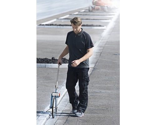 Mann mit Messrad auf der Straße in Arbeitskleidung