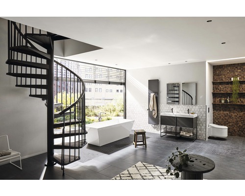 Salle de bains avec escalier en colimaçon, baignoire îlot, meuble-lavabo, radiateur et toilettes.