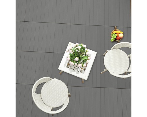 Szene mit grauen Terrassendielen, Gartentisch und Stühlen aus Rattan