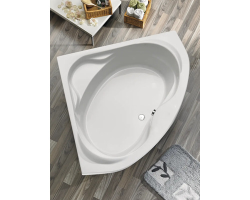 Baignoire d''angle dans une salle de bains avec tapis de bain et tables d''appoint