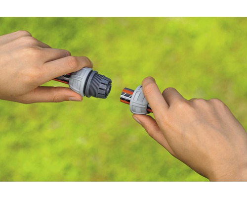 Zwei Hände verbinden eine Schlauchkupplung mit einem Gartenschlauch.