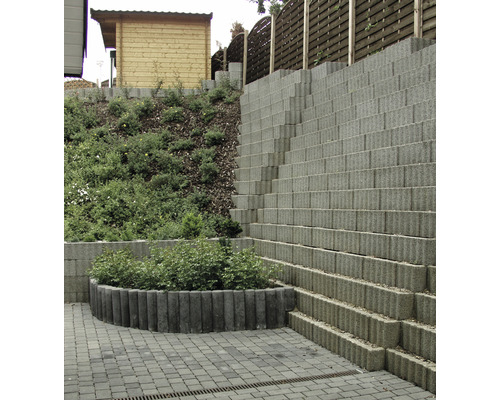 Gestufter Garten mit Stützmauer aus Betonsteinen und bepflanztem Beet