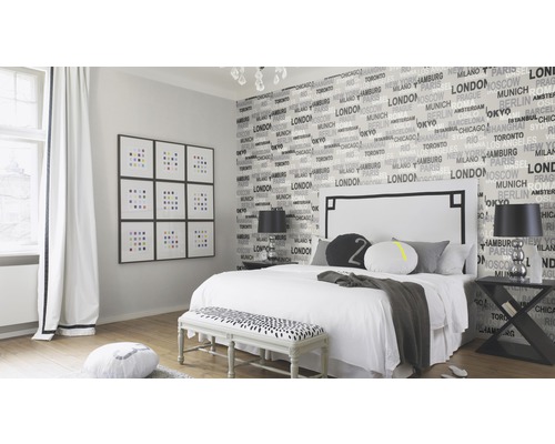 Schlafzimmer mit Bett, Nachttischen, Sitzbank und Fotowand mit Städte-Tapete