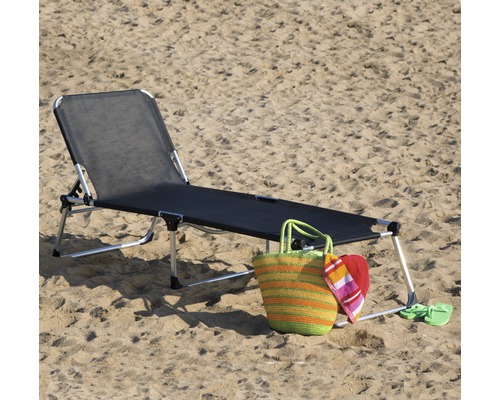Chaise longue de plage avec sac de plage et accessoires dans le sable