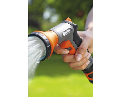Eine Hand hält eine Gartendusche von Gardena, aus der Wasser strömt.