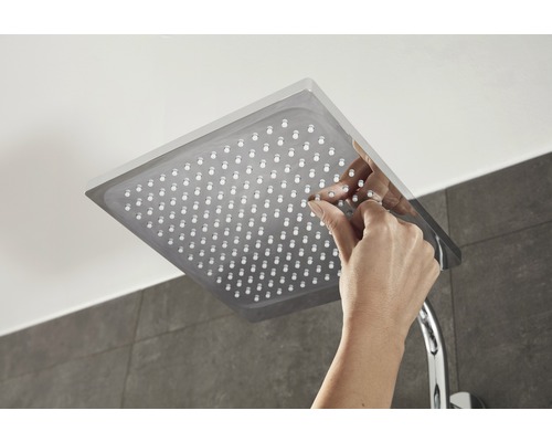 Quadratische Duschbrause mit Hand, die die Düsen reinigt