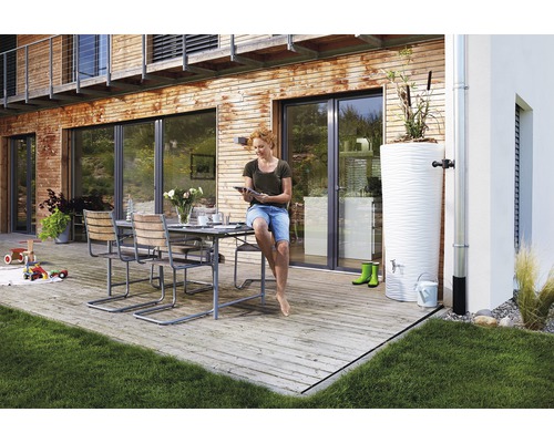 Außenszene mit Gartenmöbeln, einem Wassertank und einer Frau, die ein Tablet nutzt