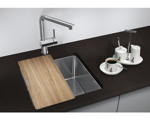 Küchenspüle mit Schneidebrett, Armatur und Kaffeegeschirr auf einer Küchentheke