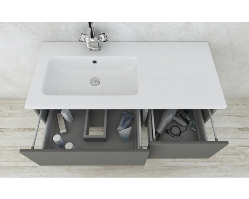 Meuble sous-vasque avec lavabo, robinet et tiroirs ouverts contenant des articles de salle de bains