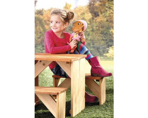 Mädchen sitzt mit Puppe an einem Kindersitzgarnitur im Garten