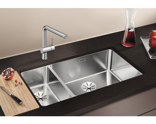 Spüle mit zwei Becken und Armatur auf einer Arbeitsplatte mit Schneidebrett und Granatapfel