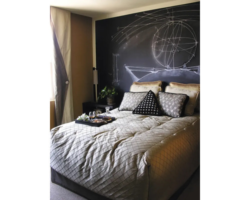 Schlafzimmer mit Tafelwand und mathematischen Zeichnungen, Bett mit Kissen und Tablett mit Getränken.