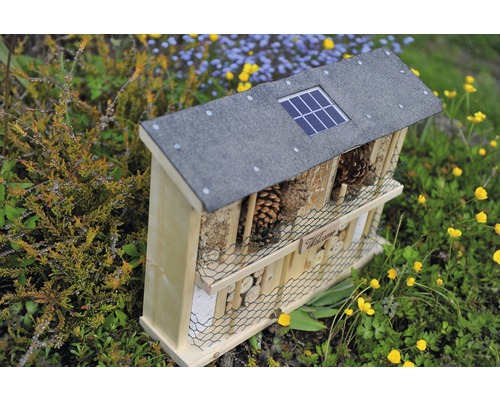 Hôtel à insectes en bois avec panneau solaire sur le toit dans le jardin
