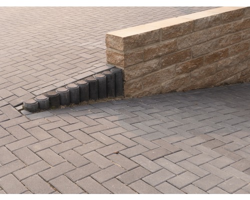 Aussenbereich mit Pflastersteinen, Palisaden und einer Steinmauer