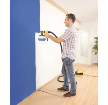 Un homme utilise un pulvérisateur de peinture pour peindre un mur dans une pièce.