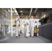 Trois personnes en combinaisons de protection marchent dans un bureau.