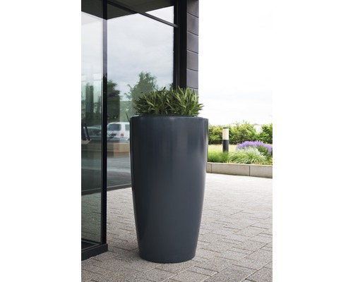 Haut pot de fleurs avec plantation devant un bâtiment