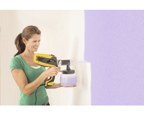 Femme utilisant un système de pulvérisation de peinture Wagner pour peindre un mur