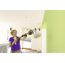 Femme utilisant un système de pulvérisation de peinture pour peindre un mur à l''intérieur.