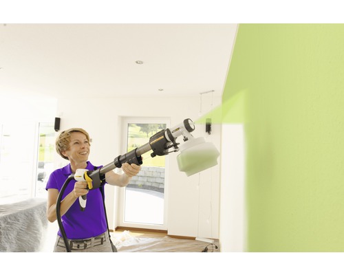 Femme utilisant un système de pulvérisation de peinture pour peindre un mur à l''intérieur.