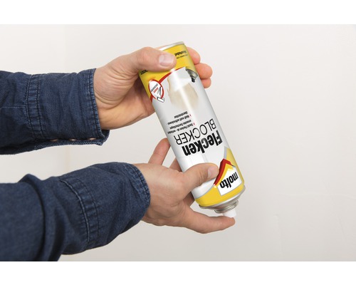 Une personne tient un aérosol anti-taches dans sa main.