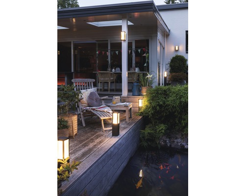 Terrasse illuminée avec mobilier de jardin et bassin avec poissons