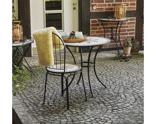 Scène de jardin avec table en mosaïque, chaise avec coussin en fourrure et décoration extérieure
