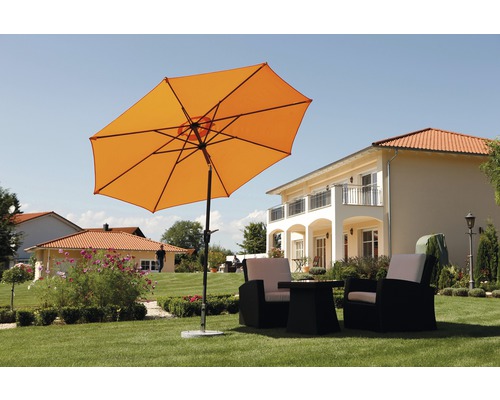 Orangefarbener Sonnenschirm mit Gartenmöbeln auf einer Rasenfläche vor einem Wohnhaus.
