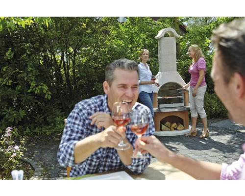 Scène avec un barbecue en pierre dans le jardin, où un groupe de personnes fait des grillades et trinque avec des verres à vin.