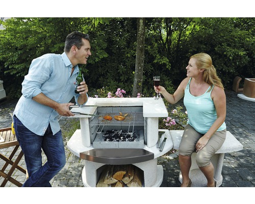 Mann und Frau beim Grillen im Garten mit Steingrill.