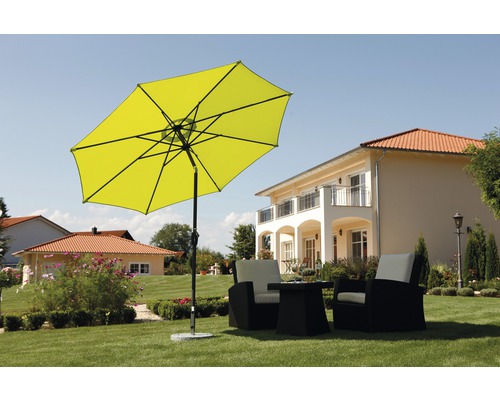 Scène avec parasol jaune et salon de jardin sur une pelouse devant une maison.