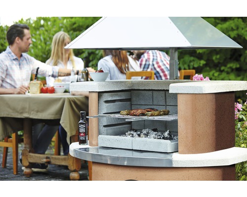 Barbecue de jardin en maçonnerie avec grillades, charbon de bois et sauce barbecue Jack Daniel''s dans le jardin avec des personnes
