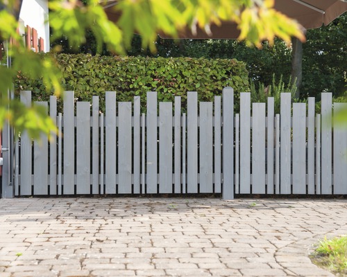 Clôture en bois grise avec planches verticales de différentes hauteurs