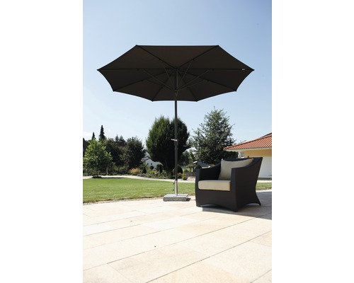 Offene Gartenszene mit einem Sonnenschirm und einem Sessel auf einer Terrasse.