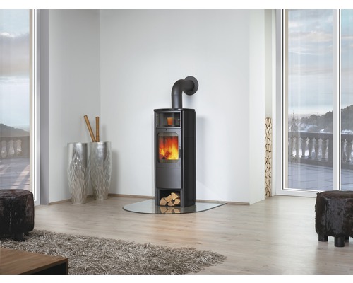 Kaminofen mit Glasbodenplatte in einem hellen Wohnraum mit grossen Fenstern.
