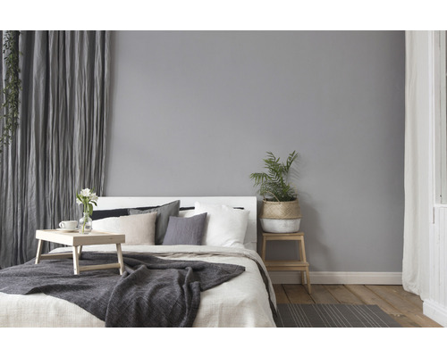 Helles Schlafzimmer mit Bett, Kissen, Decke, Vorhängen und Pflanzen