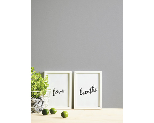 Dekorative Bildersets mit den Aufschriften Liebe und Atmen, zusammen mit Kräutern im Topf und Limetten.