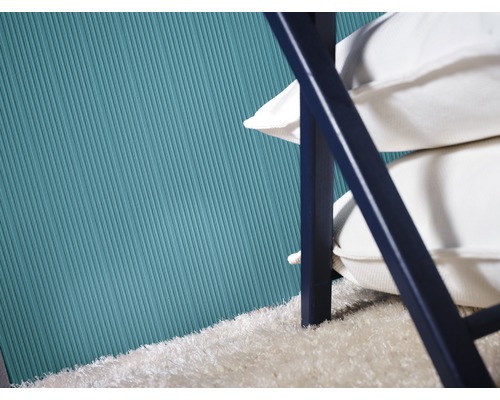 Vue détaillée d''un mur avec du papier peint rainuré, une pile de coussins et un tapis