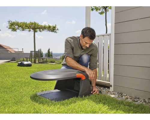 Mann installiert einen Rasenmähroboter im Garten