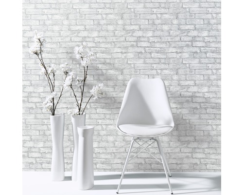 Szene mit einer weißen Wandtapete in Backsteinoptik, einer Vase mit Blumen und einem Stuhl