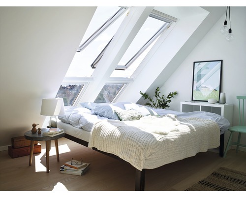 Helles Schlafzimmer im Dachgeschoss mit Dachfenstern, Bett und Nachttisch