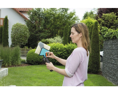 Femme regardant une brosse de surface dans le jardin.