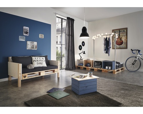 Wohnzimmer mit Möbeln aus Paletten, darunter ein Sofa, ein Tisch und ein Kleiderständer