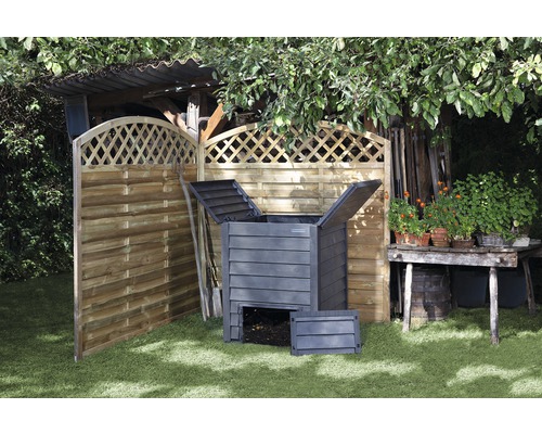 Kompostsammelbehälter neben Holzzaun im Garten