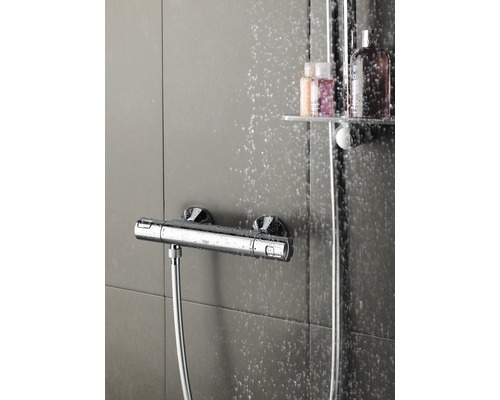 Photo d''un robinet de douche avec flexible de douche devant un fond carrelé