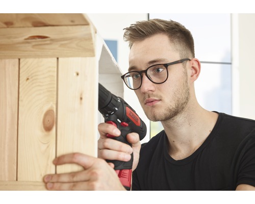 Mann arbeitet mit einem Akku-Schrauber an einem Holzregal