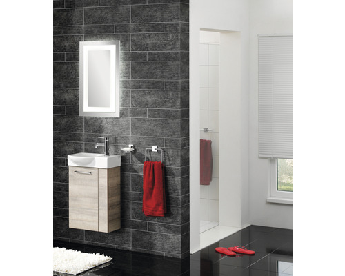 Salle de bains moderne avec lavabo, miroir éclairé, carreaux foncés et douche.