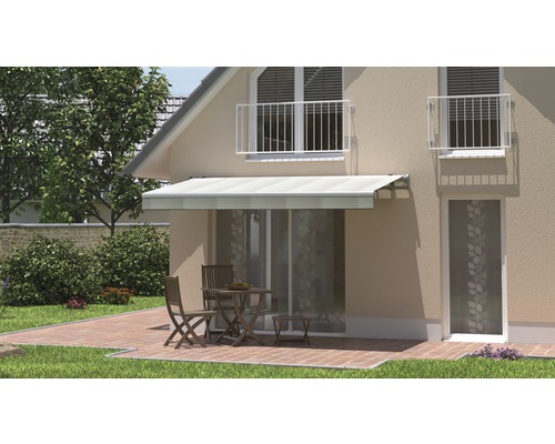 Façade de maison avec store au-dessus de la terrasse avec table et chaises