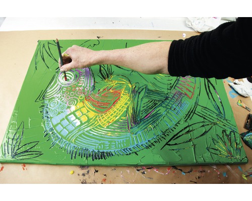 Une personne peint un tableau de poisson abstrait sur une toile.